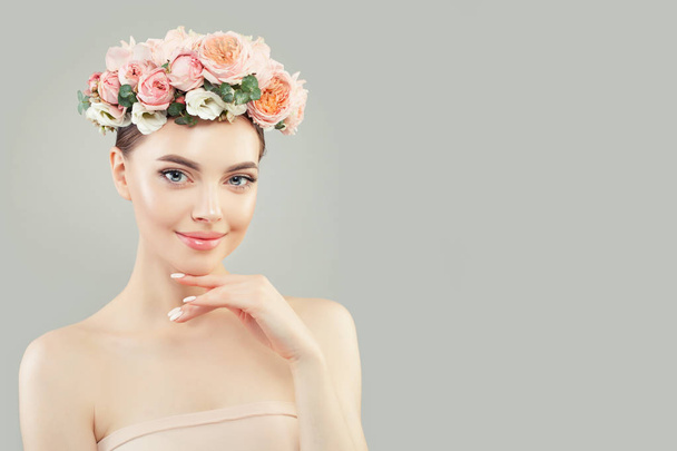 Vrolijke jonge vrouw met heldere huid en bloemen - Foto, afbeelding