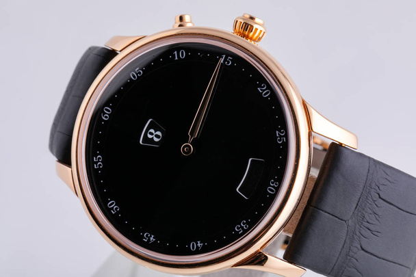 Golden wristwatch with black dial, black clockwise, chronograph on black leather strap  on white background - Photo, Image
