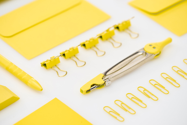 selective focus of yellow paper clips, compasses, envelopes, pen and eraser on white background - Photo, Image