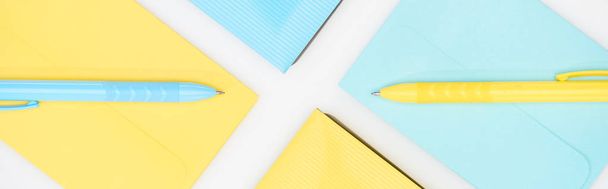 panoramatický záběr z modrých a žlutých složek, obálky a pera izolované na bílém - Fotografie, Obrázek