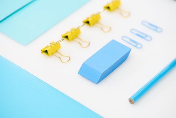 flat lay of blue paper clips, eraser, folder, pencil, envelope and yellow paper clips - Photo, Image
