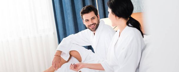 panoramic shot of cheerful man looking at woman in hotel room  - Photo, image