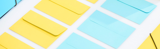 panoramic shot of yellow and blue envelopes and folders on white background - Fotografie, Obrázek
