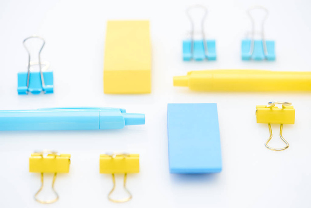 selektiver Fokus von gelben und blauen Bleistiften, Radiergummis und Büroklammern auf weißem Hintergrund - Foto, Bild