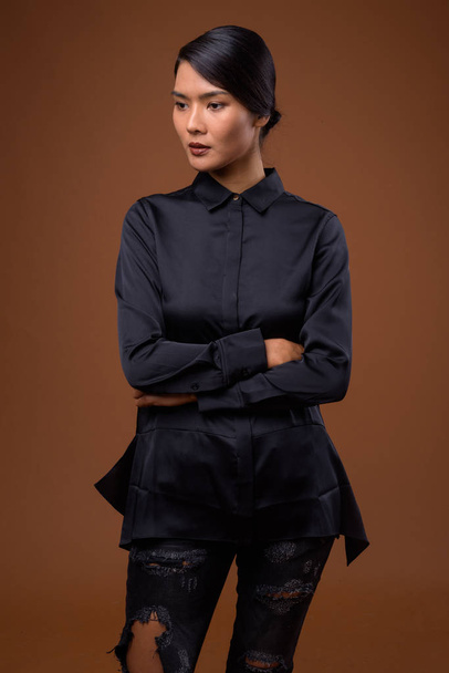Studio strzał z piękny Asian businesswoman przeciwko brązowy ciemny - Zdjęcie, obraz