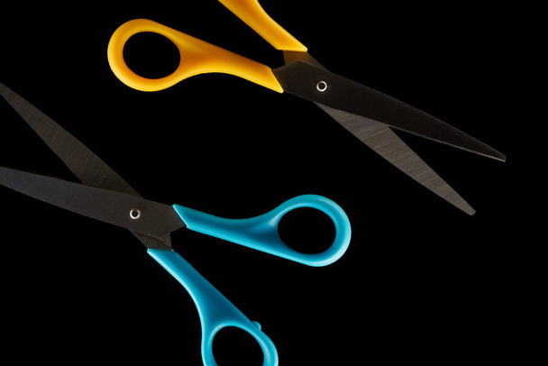 top view of blue and yellow scissors isolated on black  - 写真・画像