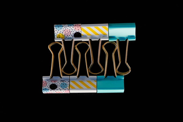 top view of yellow, blue and textured paper clips isolated on black  - Valokuva, kuva