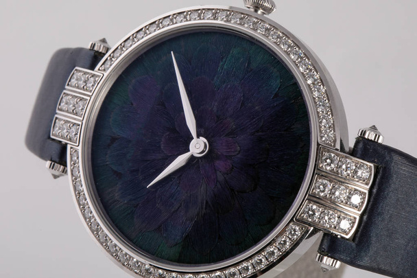 白い背景に隔離された黒い革のストラップに石の縁を持つ青いダイヤルシルバーの手を持つシルバーの女性の腕時計 - 写真・画像