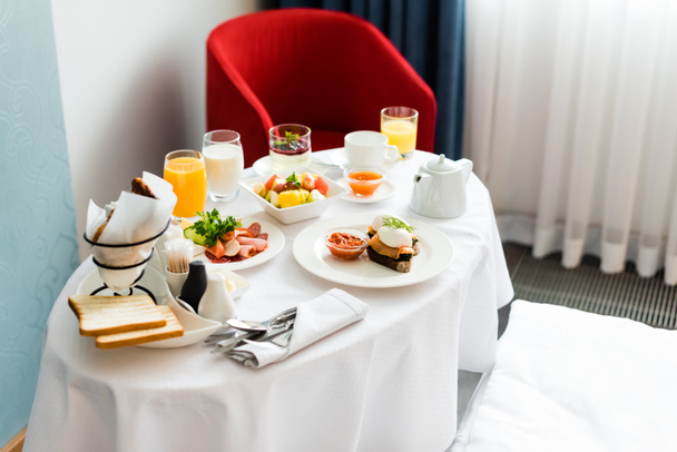 вкусный завтрак возле стаканов с апельсиновым соком и молоком на столе
  - Фото, изображение