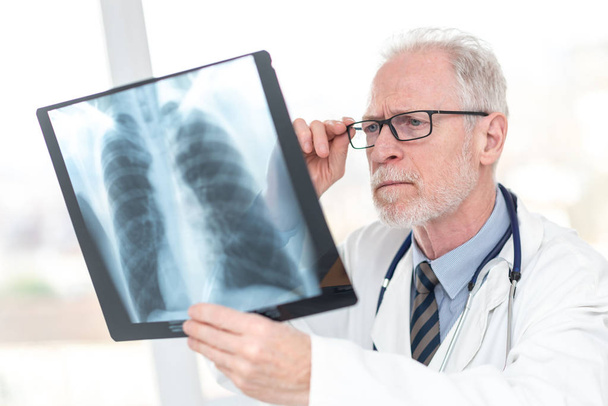 Medico anziano che guarda i raggi X
 - Foto, immagini