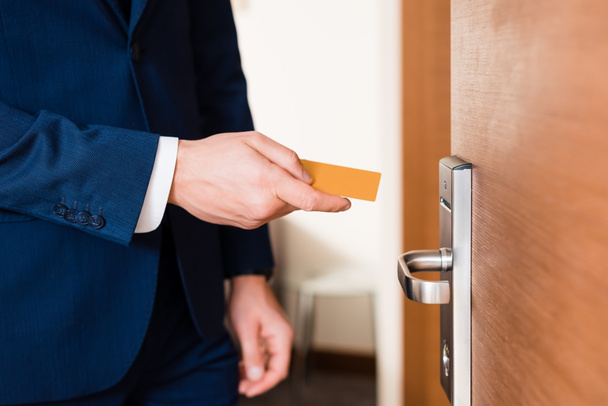 обрізаний вид бізнесмена, що тримає готельну картку, стоячи біля дверей
  - Фото, зображення