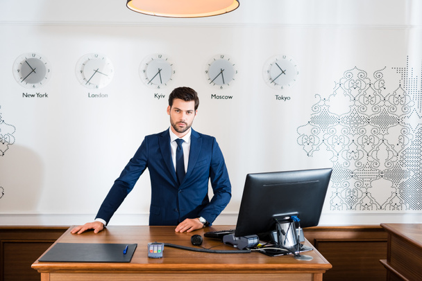 handsome receptionist standing at reception desk in hotel  - Photo, Image