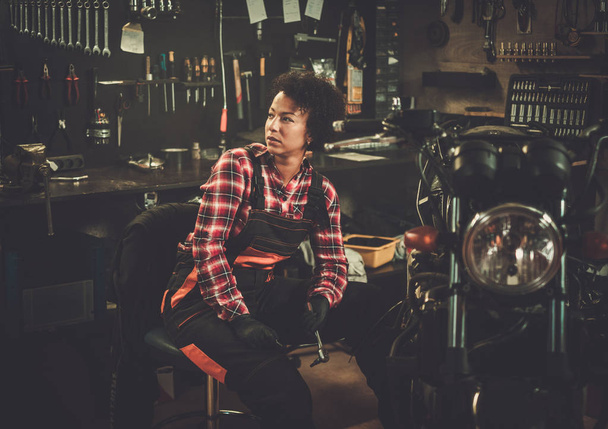 Mujer mecánica afroamericana reparando una motocicleta en un taller
 - Foto, Imagen