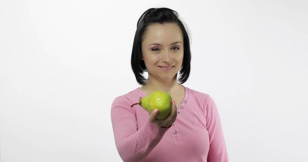 Young beautiful woman with big, fresh, juicy, green pear. Offer bite to viewer - Photo, Image
