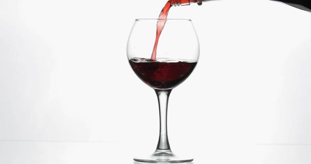 Rose wijn. Rode wijn pour in wijn glas over witte achtergrond - Foto, afbeelding