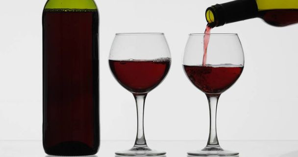 ロゼワイン赤ワインは白い背景の上にワイングラスに注ぐ - 写真・画像