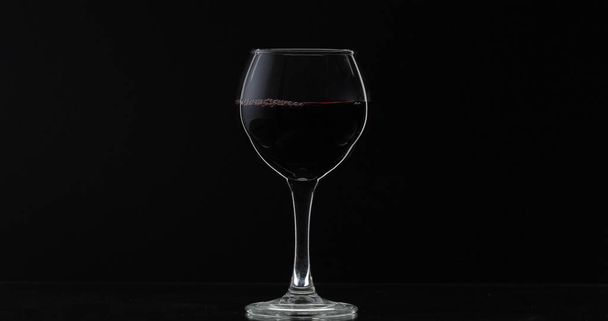 Rose wine. Red wine in wine glass over black background. Silhouette - Fotoğraf, Görsel