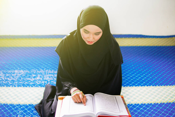 A fiatal muszlim nő Al Koránt szavalt egy mecsetben. Az Al Korán egy iszlám szent könyv. - Fotó, kép