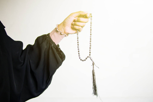 Χέρι μουσουλμανικής γυναίκας που προσεύχεται ενώ κρατά χάντρες προσευχής, τασβ πάνω από το λευκό φόντο - Φωτογραφία, εικόνα
