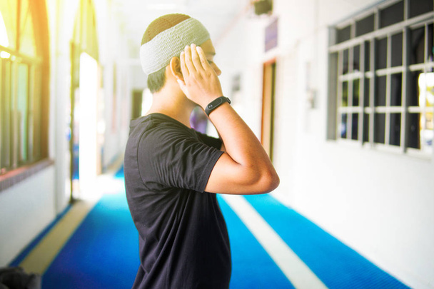 Νεαρός μουσουλμάνος προσεύχεται με τα χέρια ψηλά για τάκμπιρ μέσα σε ένα τζαμί - Φωτογραφία, εικόνα