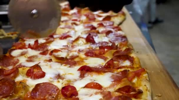Close up for hands of chef baker in black cooking gloves cutting pizza at the kitchen, delicious italian food concept. Frame. Man cuts freshly prepared pizza slices with a special knife. - Imágenes, Vídeo