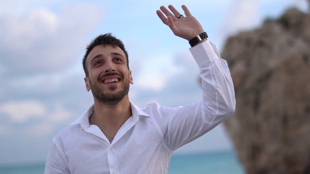 Young handsome man happily smiling with an amazed expression to others and waving hand. Cyprus. Paphos - Filmati, video