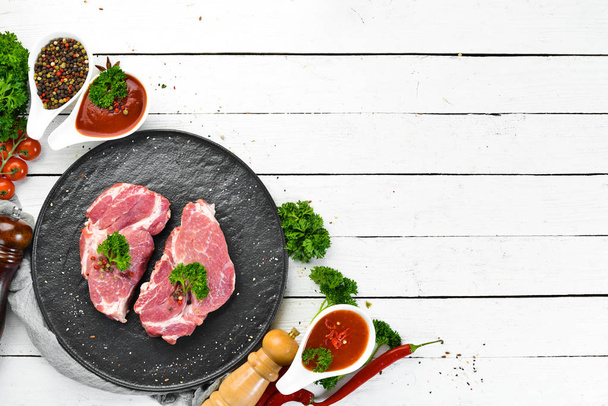Raw pork steak. Fresh meat. On a plate of spices and herbs. Top view. Free space for your text. - Foto, Imagen