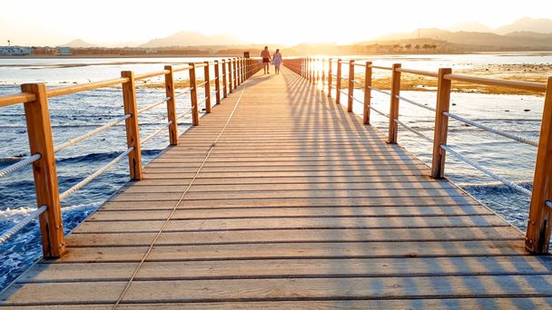 Gyönyörű kép hosszú, fából készült mólón az EA. csodálatos naplemente a hídon az óceán - Fotó, kép