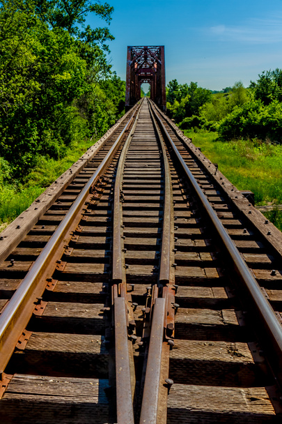 όμορφη συγκλίνουσες γραμμές από τις ράγες του ένα παλιό σιδηροδρόμου ικρίωμα με μια παλιά εικονική σιδερένια γέφυρα ζευκτόντων - Φωτογραφία, εικόνα
