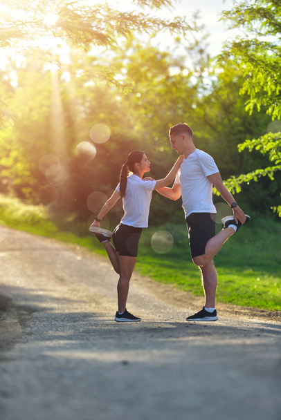 Young couple stretching legs on a road at the park - Фото, зображення
