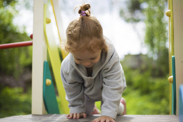 happy beautiful little redhead girl climbs the slide on the playground - Foto, immagini