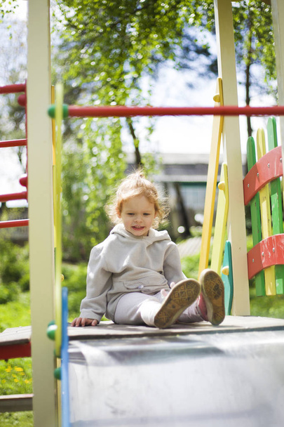 щаслива красива маленька руда дівчинка піднімається на слайд на дитячому майданчику
 - Фото, зображення