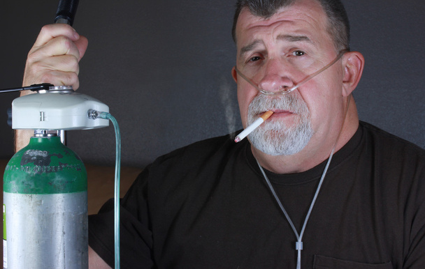 Homem adulto fumando enquanto usa Cânula de Oxigênio
 - Foto, Imagem