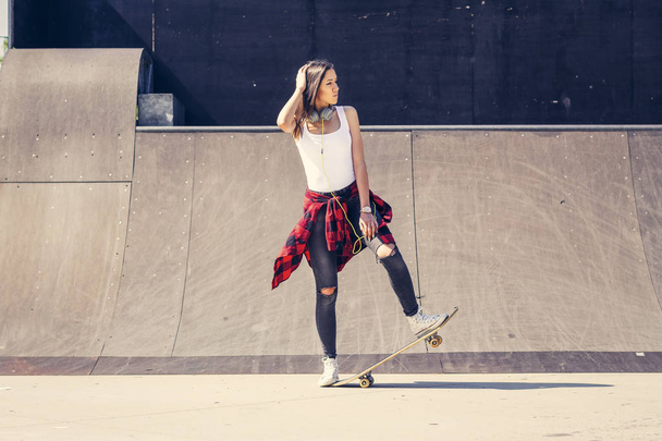 Милая женщина держит скейтборд в скейт-парке
 - Фото, изображение