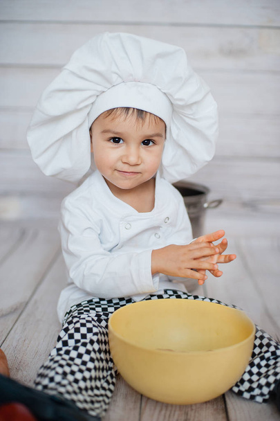Half-length portrait of a little chef. Cute little child in apron and chef hat is looking at camera. - Fotó, kép