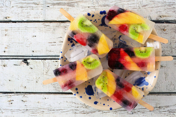 Gezonde gemengde fruit zomer popsicles. Bovenstaande weergave in Bowl tegen een witte houten achtergrond. - Foto, afbeelding