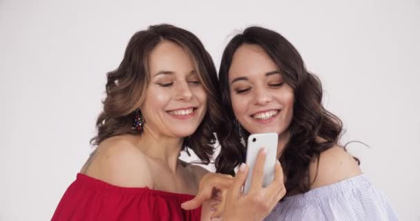 Twee mooie vrouwen kijken naar de telefoon en het kiezen van de beste selfie  - Video