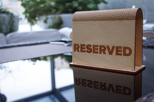 Дерев'яна вивіска з написом, зарезервованим на скляному столі в модному ресторані або кафе, вибірковий фокус
 - Фото, зображення