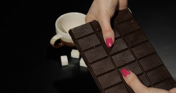 Woman holds black chocolate bar. Close-up shot of woman fingers - Photo, Image