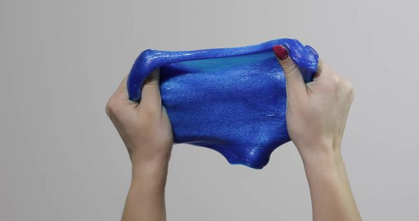 Des mains de femme jouant avec une substance gluante bleue curieusement satisfaisante. Antistress
 - Photo, image