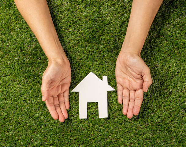 Концептуальная картина женских рук, защищающих белый дом на зеленом поле вид сверху и копировать пространство в инвестиции в недвижимость Сохранение и покупка ипотечного страхования и банковской концепции
. - Фото, изображение
