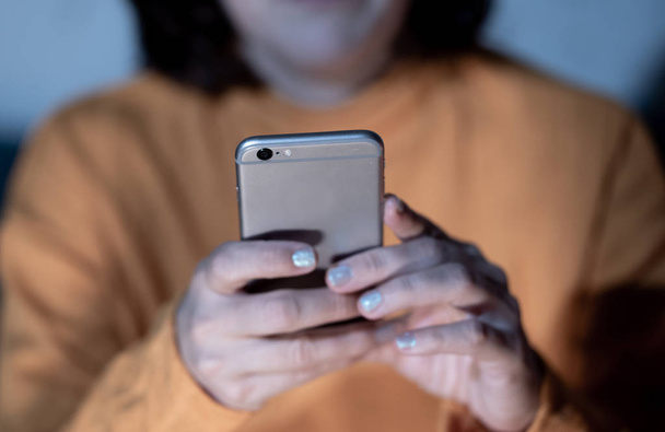 Close up of teenager or adult woman playing online and sending text on smart phone with a colorful background light from the screen in Mobile addiction Internet gaming Connections and New technology. - 写真・画像