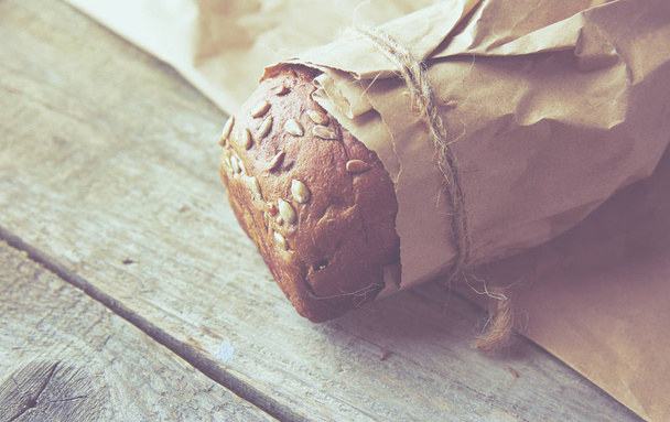 A loaf of Bread packed in paper on wooden table. - Photo, Image