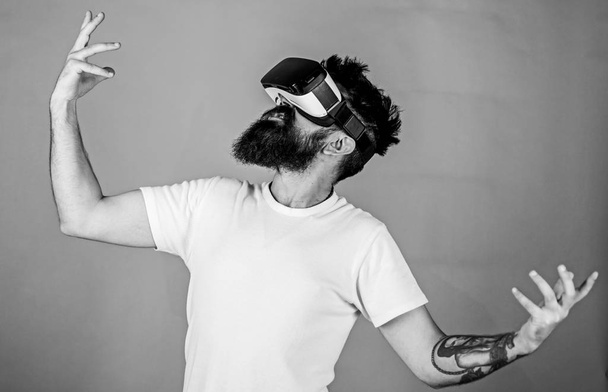 Hipster on enthusiastic face having fun in virtual reality. Virtual party concept. Guy with head mounted display dance in virtual reality. Man with beard in VR glasses dancing, green background - Foto, Imagen