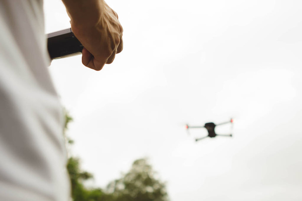 Vue arrière des mains tenant une caméra à télécommande de drone tout en volant dans le ciel
 - Photo, image