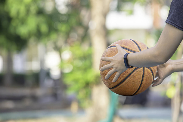 Baloncesto de cuero en la mano de una mujer que lleva un reloj Árbol borroso de fondo en el parque
. - Foto, Imagen