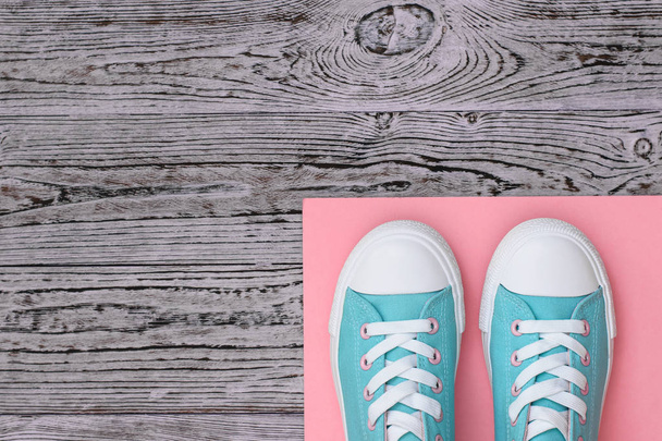 Zapatillas de deporte de color turquesa en una alfombra rosa en un suelo de madera. Estilo deportivo. Puesta plana
. - Foto, imagen