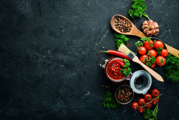 A set of tomato sauces on a black stone background. Ketchup, barbecue sauce, tomato sauce. Top view. Free space for your text. - Foto, Imagem