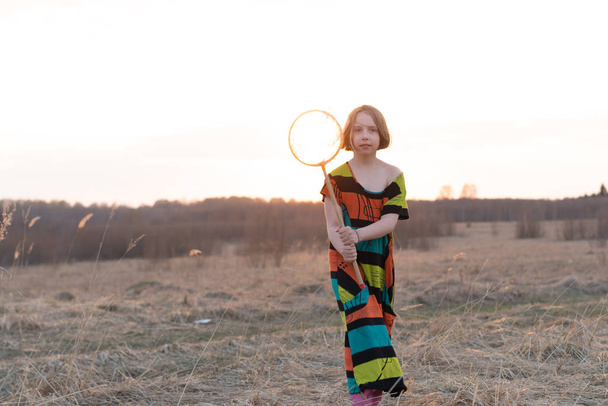 niña en un campo en primavera con una red, de pie en un vestido de color
 - Foto, Imagen