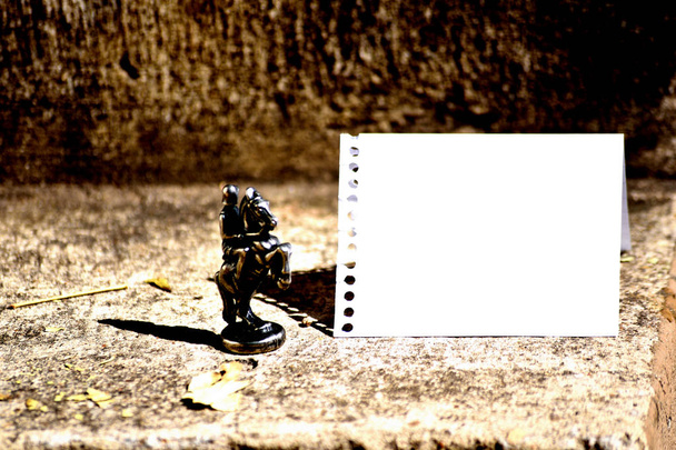 Bronze Chess Piece Knight Chessman Set ao lado e enfrentando em branco espiral Notebook Folha rasgada e dobrada ao meio com folhas secas pisoteadas espalhadas ao redor
 - Foto, Imagem